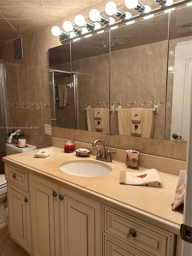 bathroom with toilet, a shower stall, tile walls, and vanity