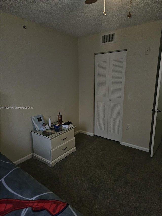 bedroom featuring baseboards, visible vents, dark colored carpet, and a textured ceiling