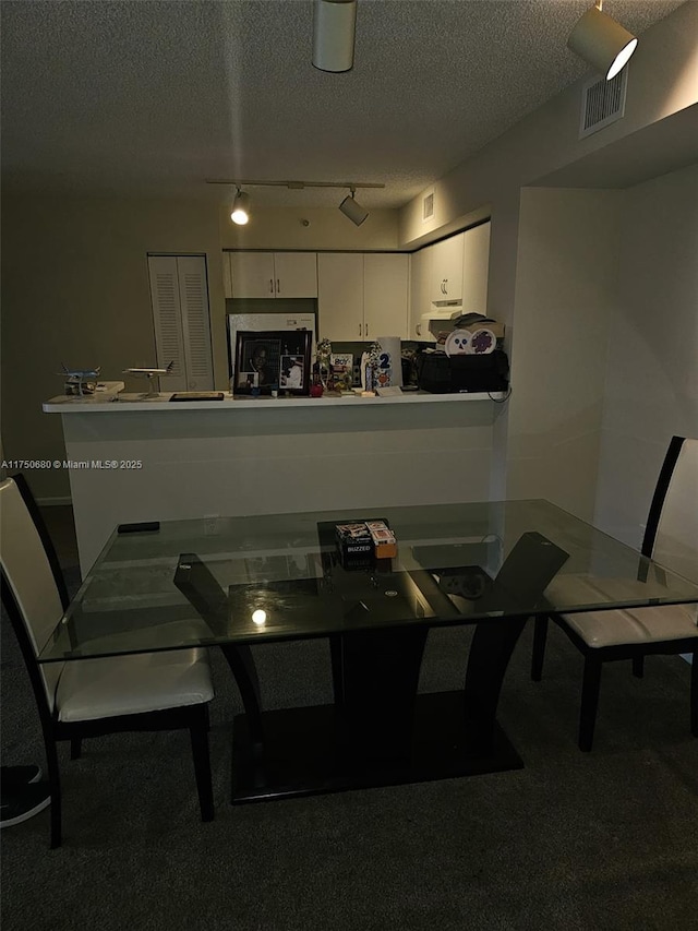 dining area featuring carpet floors, visible vents, and a textured ceiling