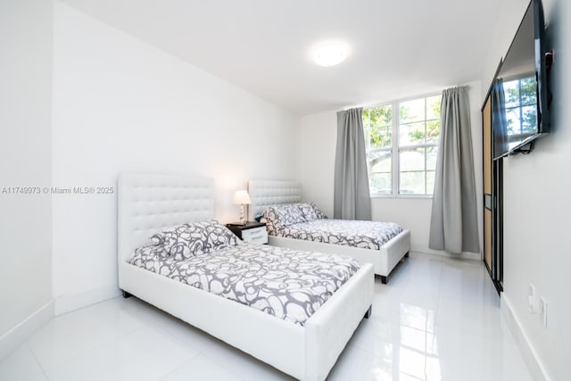 bedroom featuring multiple windows, baseboards, and light tile patterned floors