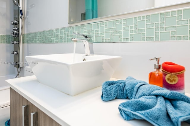 room details with a shower, vanity, toilet, and decorative backsplash