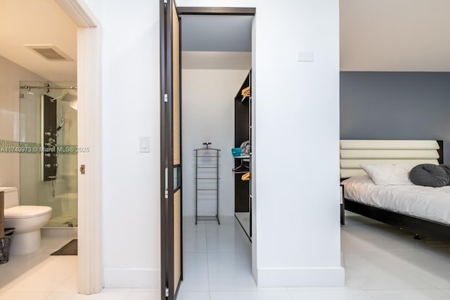 bedroom with light tile patterned floors, a closet, visible vents, and ensuite bathroom