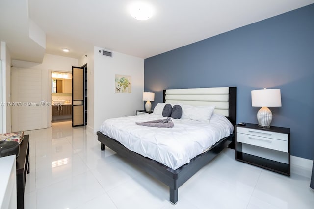 bedroom with visible vents, connected bathroom, baseboards, and light tile patterned floors