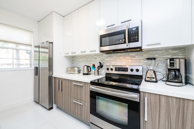 kitchen with modern cabinets, appliances with stainless steel finishes, white cabinetry, and light countertops