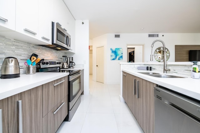 kitchen featuring modern cabinets, appliances with stainless steel finishes, white cabinets, and light countertops