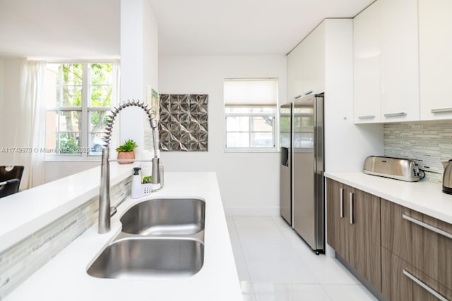 kitchen with stainless steel fridge with ice dispenser, modern cabinets, light countertops, white cabinetry, and backsplash