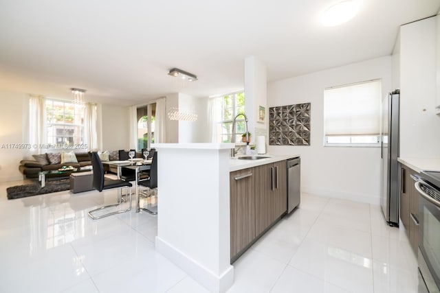 kitchen featuring a wealth of natural light, light countertops, appliances with stainless steel finishes, open floor plan, and a sink