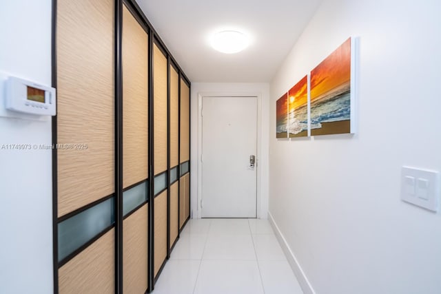 corridor with light tile patterned floors and baseboards