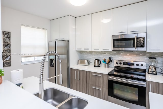 kitchen featuring stainless steel appliances, light countertops, white cabinetry, and modern cabinets