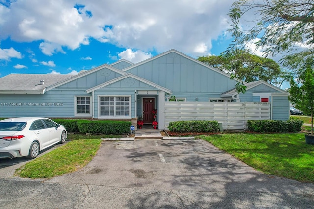 view of front facade featuring uncovered parking, a front lawn, and board and batten siding