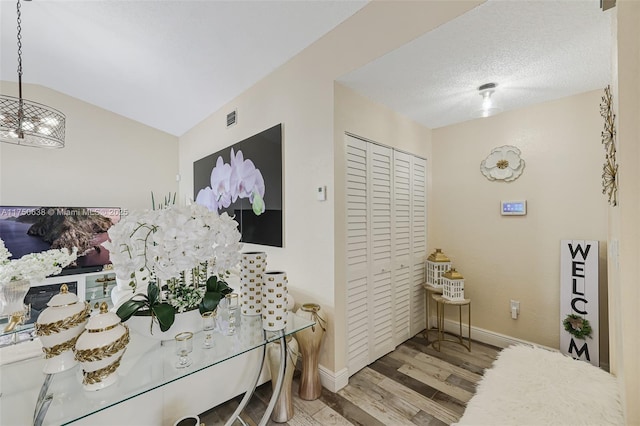 interior space featuring vaulted ceiling, light wood-type flooring, visible vents, and baseboards