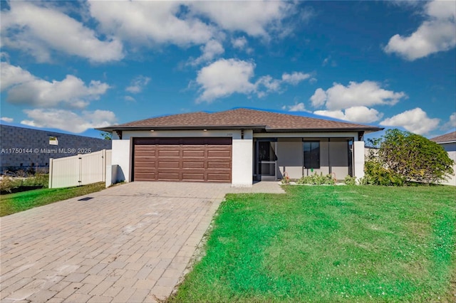 single story home featuring an attached garage, fence, decorative driveway, a front lawn, and stucco siding