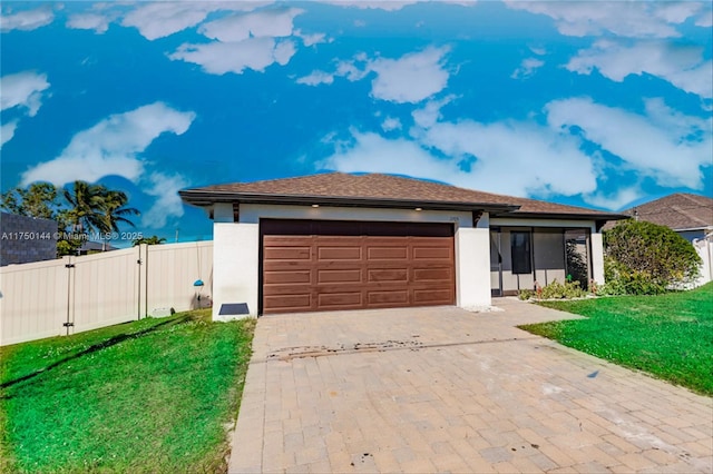 view of front facade featuring a front yard, decorative driveway, fence, and an attached garage