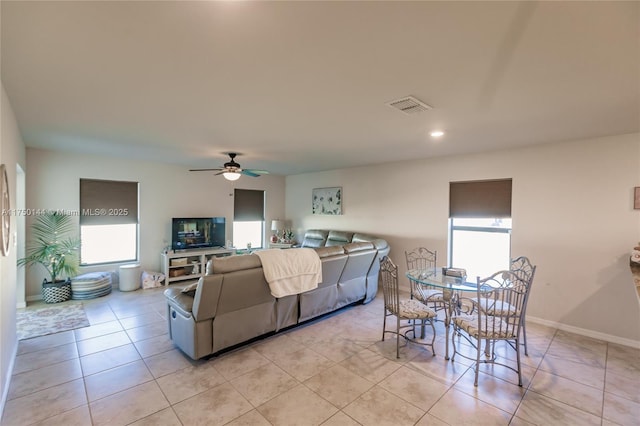 living room with light tile patterned floors, ceiling fan, visible vents, and baseboards