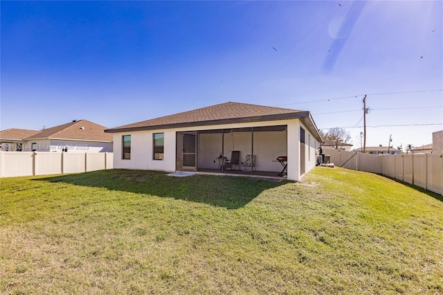 rear view of house with a lawn, a fenced backyard, and stucco siding