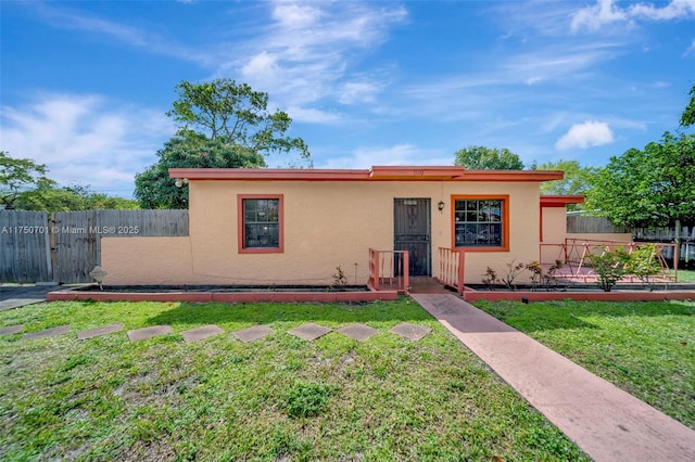 view of front of house featuring a front yard, fence, and stucco siding