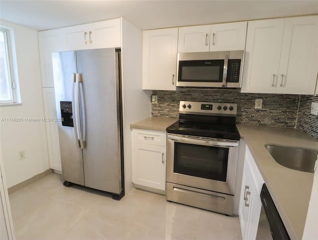 kitchen with tasteful backsplash, appliances with stainless steel finishes, white cabinets, and light countertops