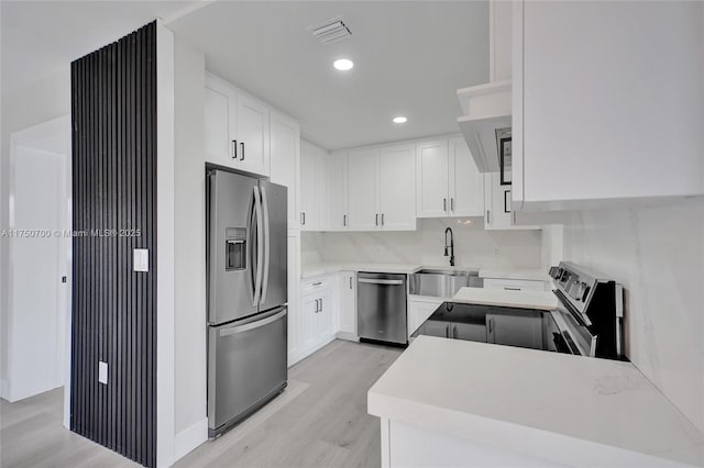 kitchen featuring visible vents, appliances with stainless steel finishes, a sink, white cabinetry, and backsplash