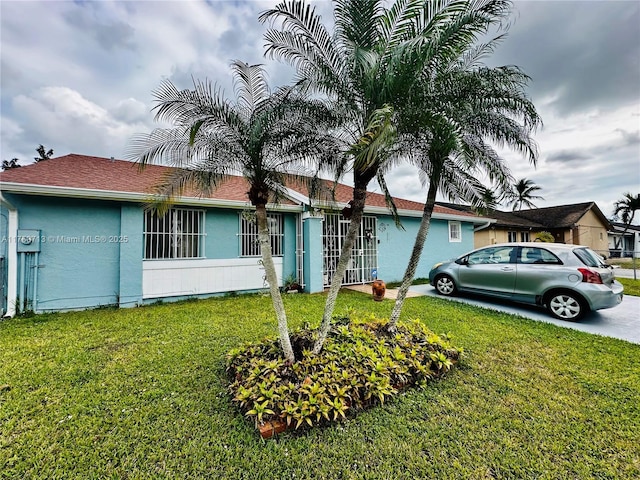 single story home featuring a front lawn, concrete driveway, and stucco siding