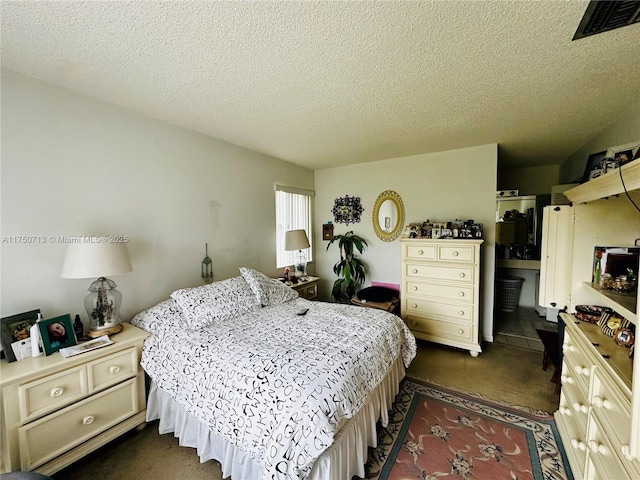 bedroom featuring a textured ceiling, dark carpet, and visible vents