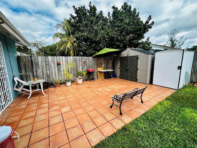 view of patio / terrace featuring a storage shed, an outbuilding, a fenced backyard, and a grill