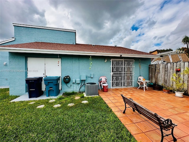 rear view of property featuring a patio, cooling unit, fence, a yard, and stucco siding