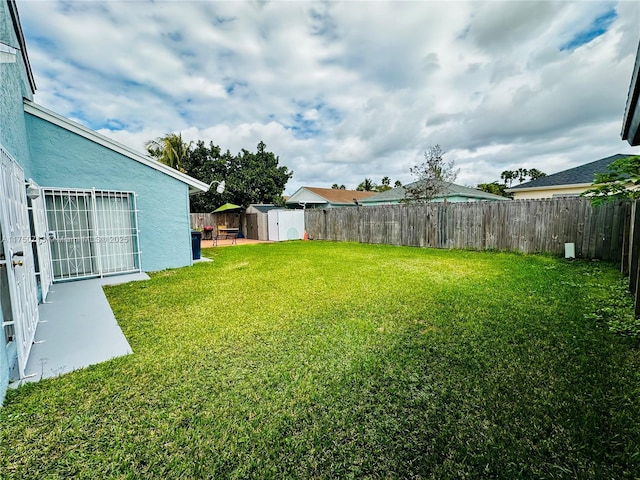 view of yard with an outbuilding, a fenced backyard, and a shed