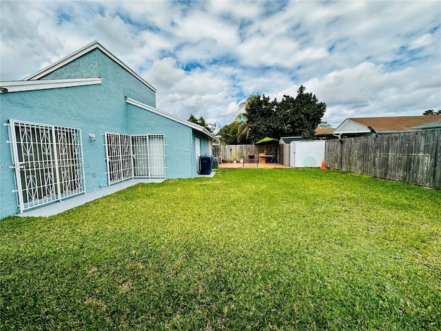 view of yard featuring a storage shed, a fenced backyard, and an outdoor structure