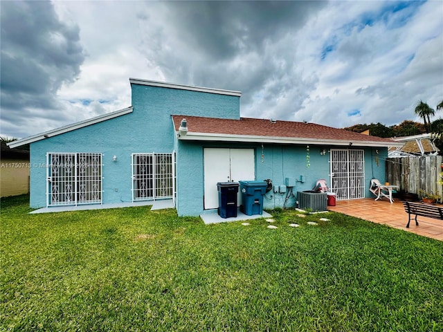 back of house featuring a patio area, a lawn, and stucco siding