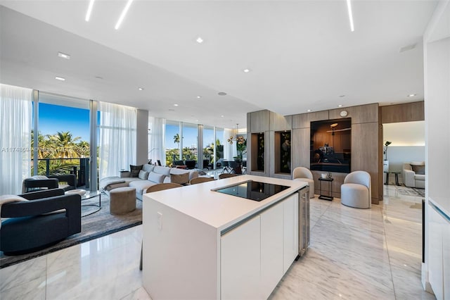 kitchen featuring marble finish floor, modern cabinets, black electric cooktop, and a wall of windows