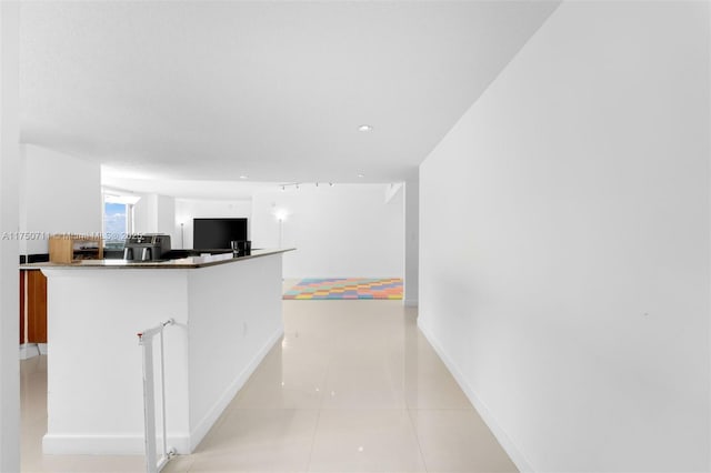 kitchen featuring white cabinetry, a peninsula, baseboards, and light tile patterned floors