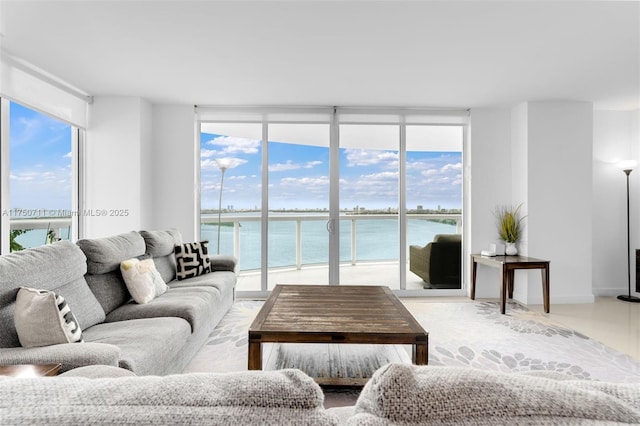 living area with baseboards, a water view, and floor to ceiling windows