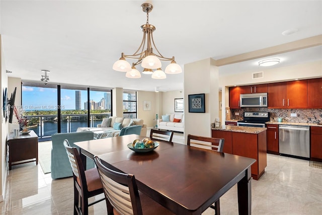 dining space featuring a city view, a notable chandelier, visible vents, a water view, and expansive windows