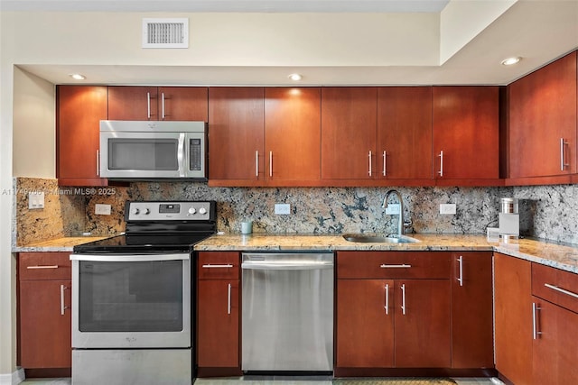 kitchen featuring a sink, visible vents, appliances with stainless steel finishes, light stone countertops, and tasteful backsplash