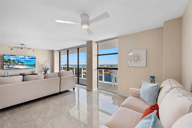 living area featuring a wall of windows, ceiling fan, and baseboards