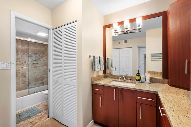 bathroom featuring enclosed tub / shower combo, toilet, vanity, visible vents, and a closet