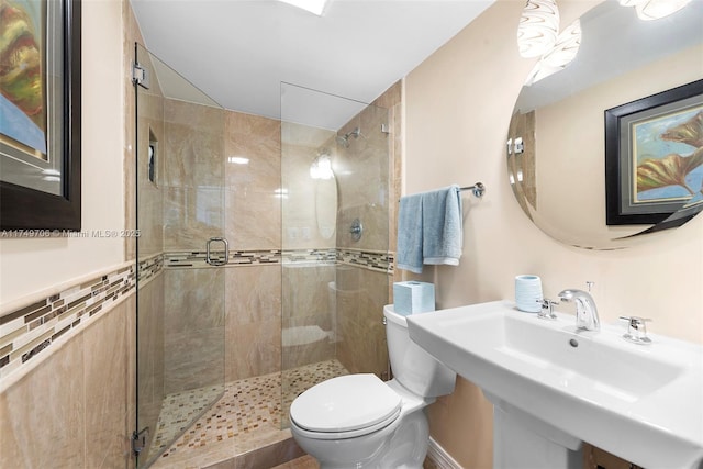 bathroom with a stall shower, a sink, and toilet