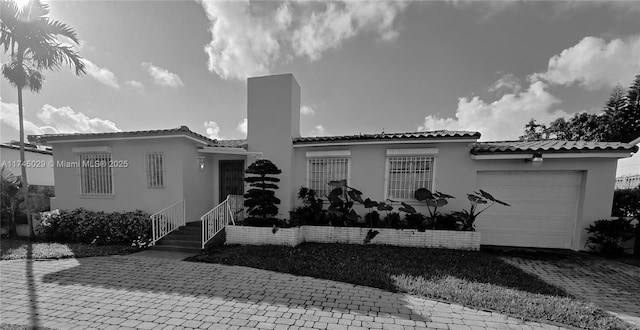 mediterranean / spanish-style house featuring a tiled roof, decorative driveway, an attached garage, and stucco siding