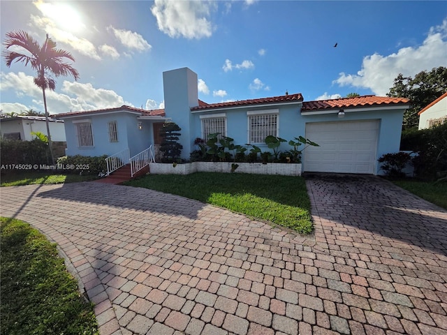 mediterranean / spanish home with decorative driveway, an attached garage, a tile roof, and stucco siding