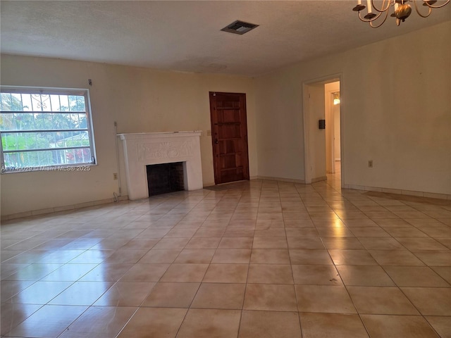 unfurnished living room with a notable chandelier, visible vents, a premium fireplace, light tile patterned flooring, and a textured ceiling