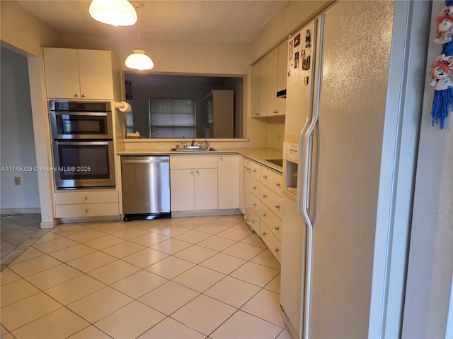 kitchen featuring light countertops, appliances with stainless steel finishes, white cabinets, a sink, and light tile patterned flooring