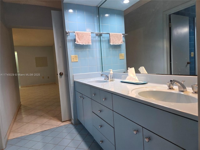 bathroom with double vanity, a sink, tile walls, and tile patterned floors