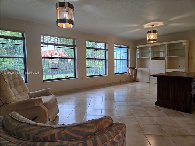 living area featuring a healthy amount of sunlight, light tile patterned floors, and a textured ceiling