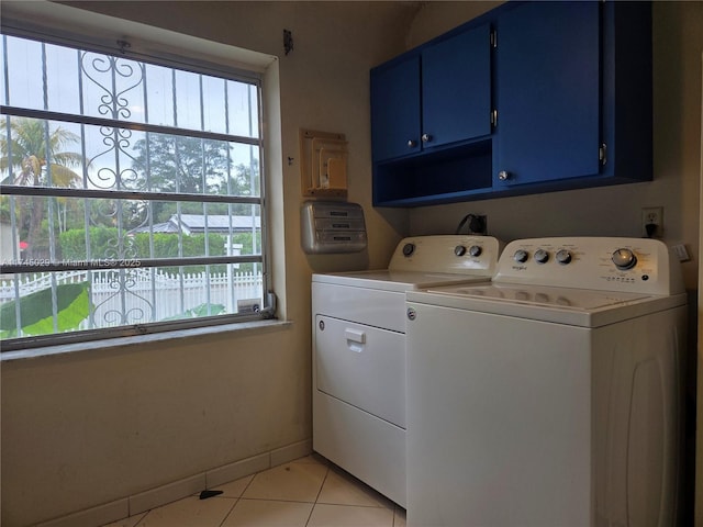 laundry room featuring cabinet space, light tile patterned floors, baseboards, and washer and clothes dryer