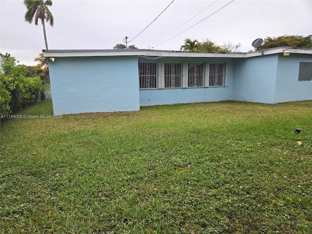 view of side of property with stucco siding and a yard