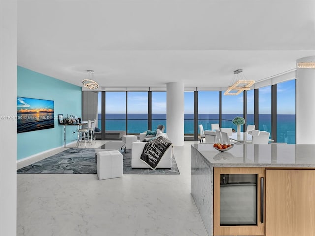 kitchen with light stone counters, wine cooler, a water view, and decorative light fixtures