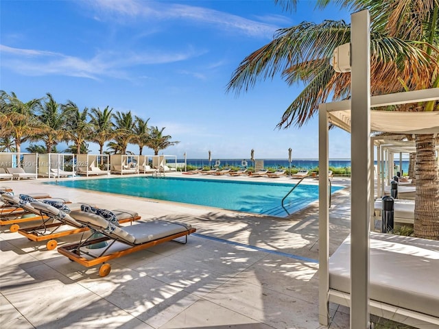 community pool featuring a water view, fence, and a patio