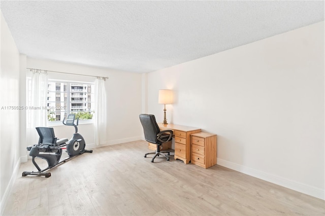 office space featuring a textured ceiling, light wood-type flooring, and baseboards