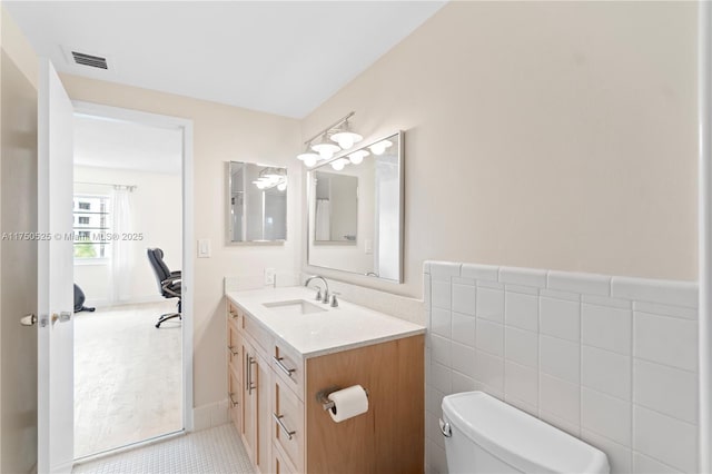 half bath featuring tile walls, visible vents, toilet, vanity, and tile patterned flooring