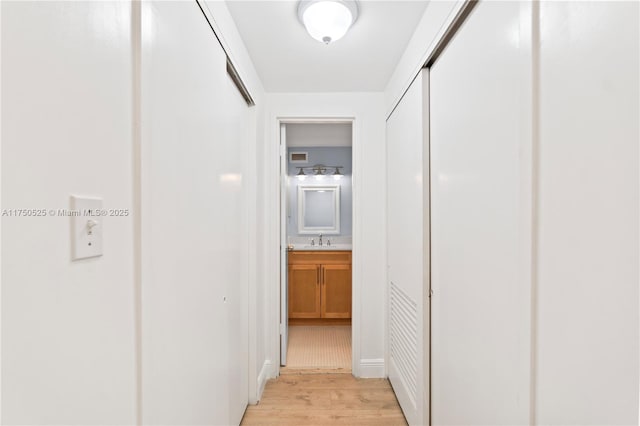 hall with light wood finished floors and a sink